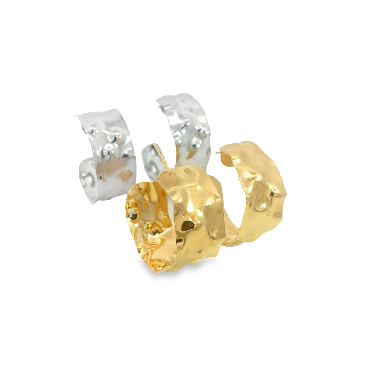 A pair of hammered gold and silver hoop earrings rest on a white surface.