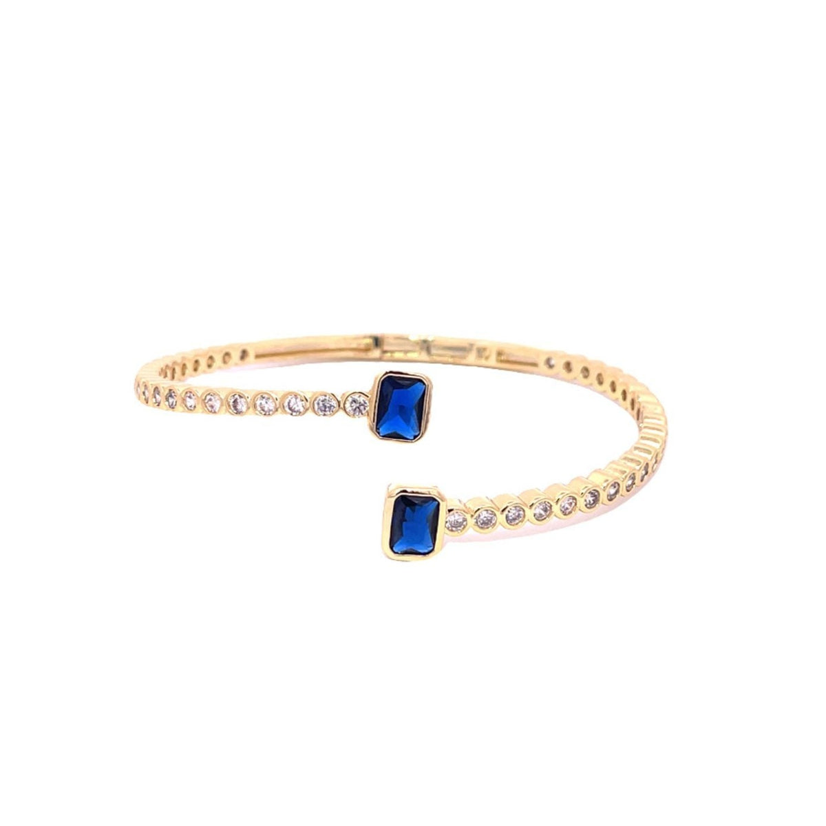 A gold cuff bracelet sparkles with round diamonds framing two rectangular blue sapphire stones at each open end.