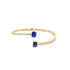 A gold open-cuff bracelet features shimmering diamond accents and two striking emerald-cut blue stones at each end.