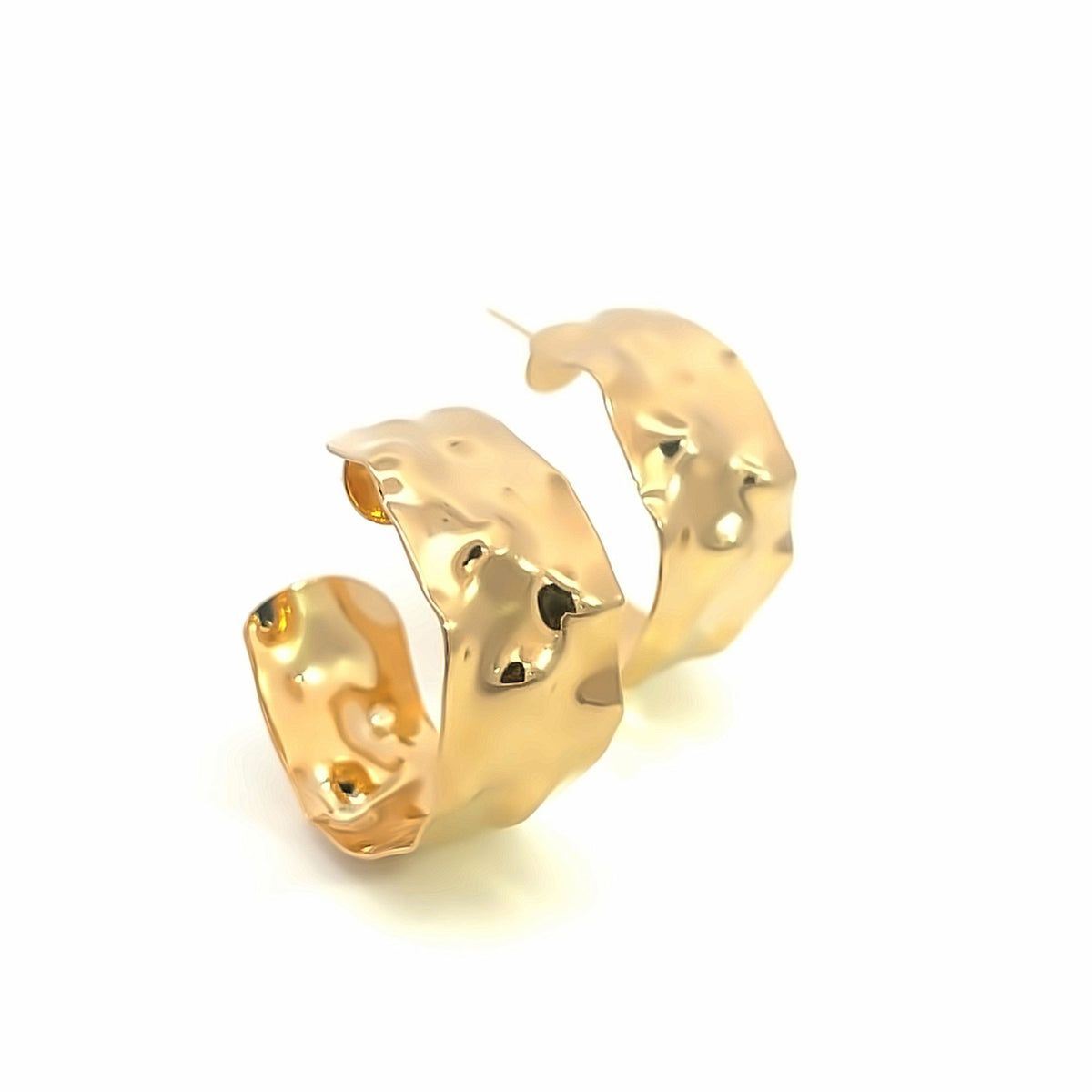 A pair of thick, hammered gold hoop earrings rests against a clean white background.