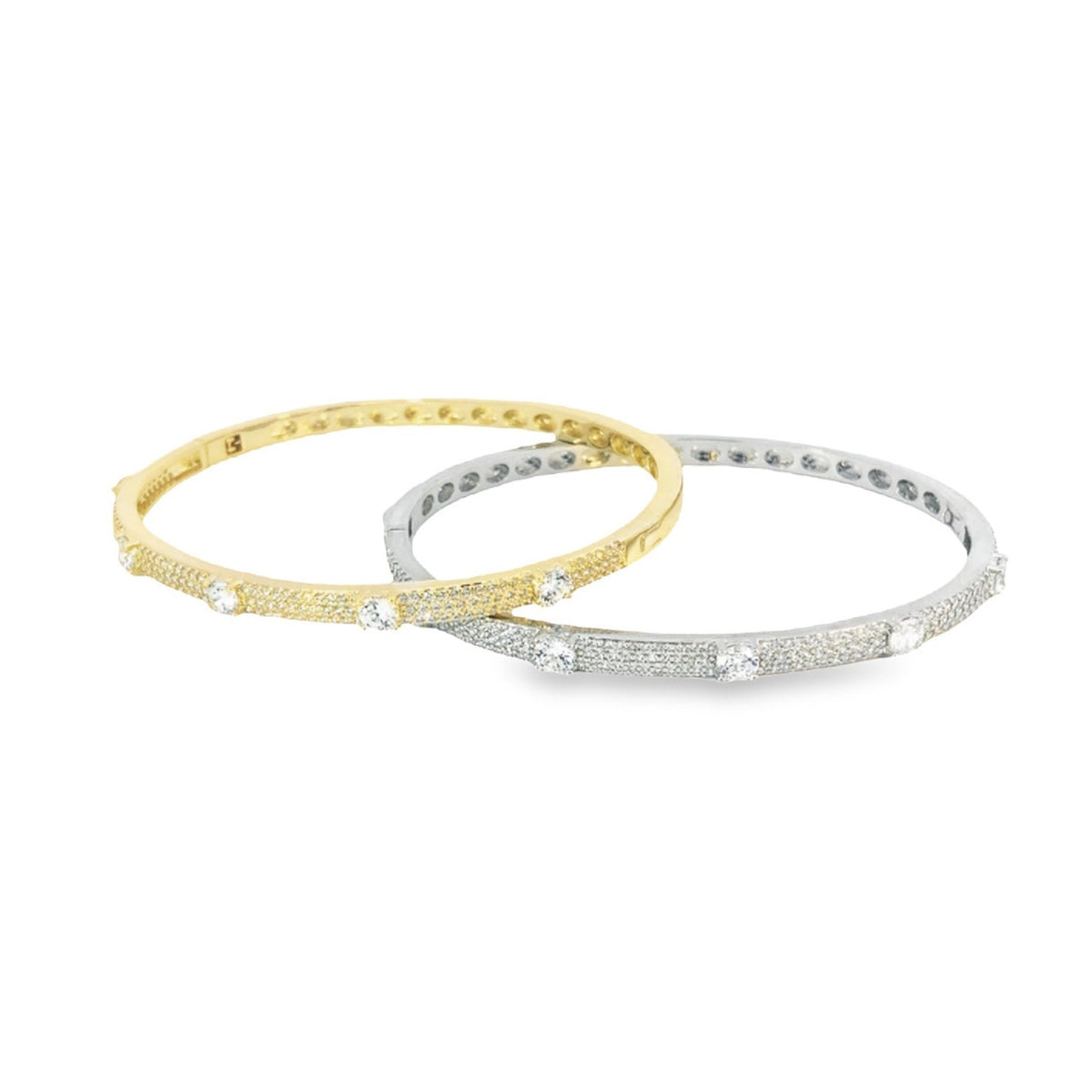 A gold and a silver diamond-pave bangle bracelet rest side-by-side against a clean white background.