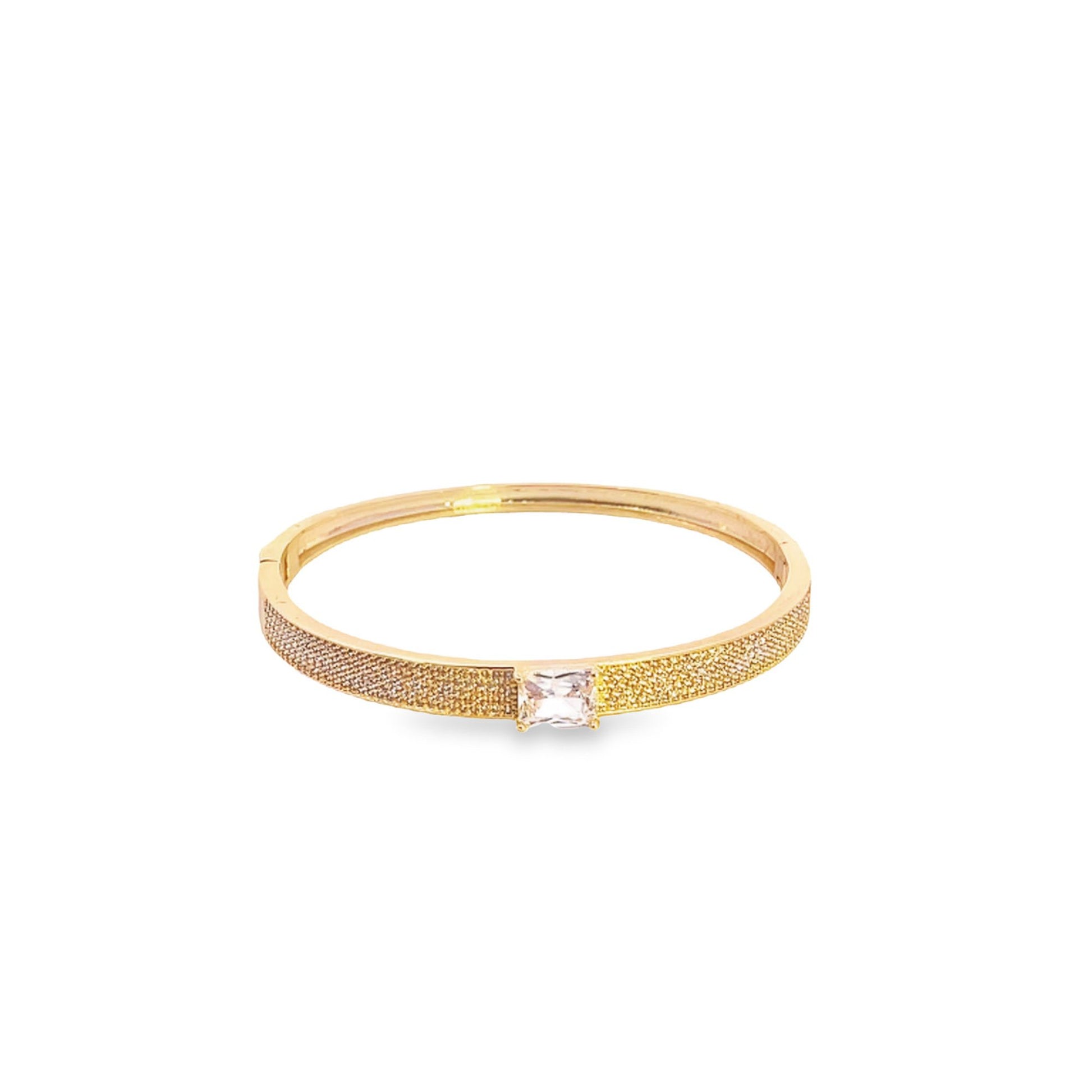 A gold-plated bangle bracelet features a shimmering pave-set band and a central emerald-cut crystal.