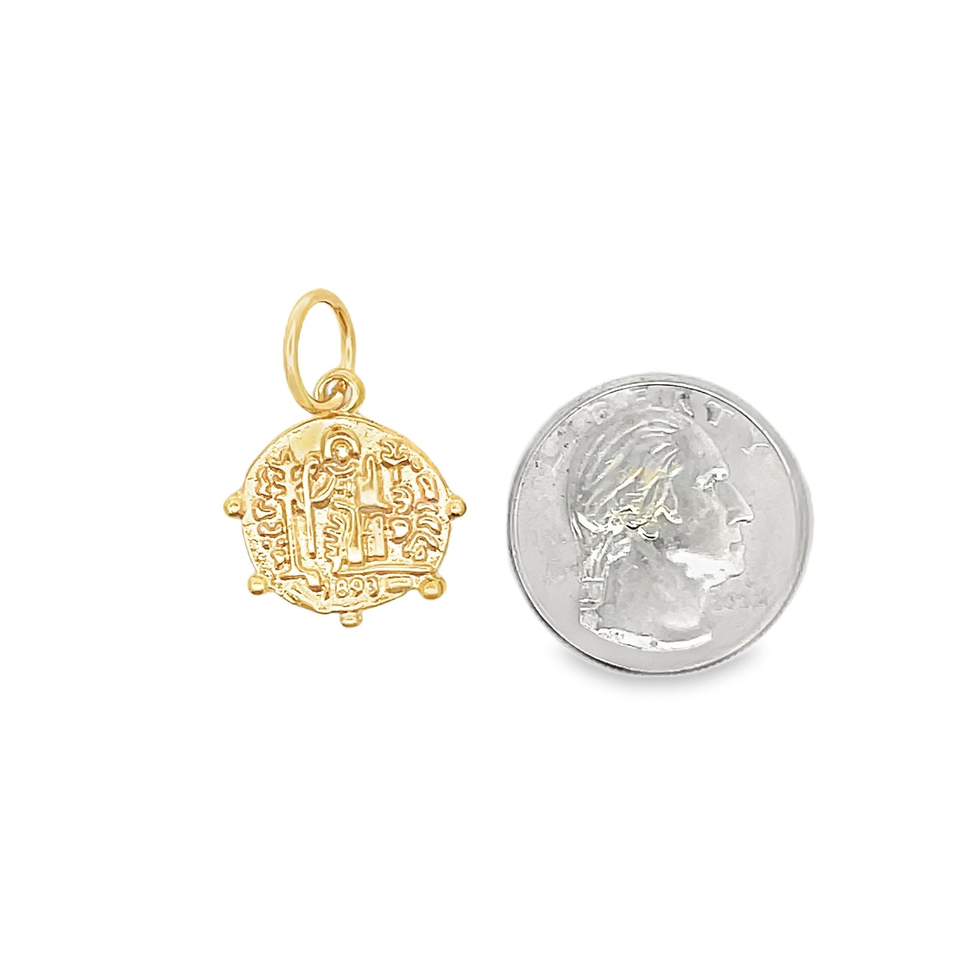 A detailed gold pendant rests beside a US quarter coin to demonstrate its actual size.