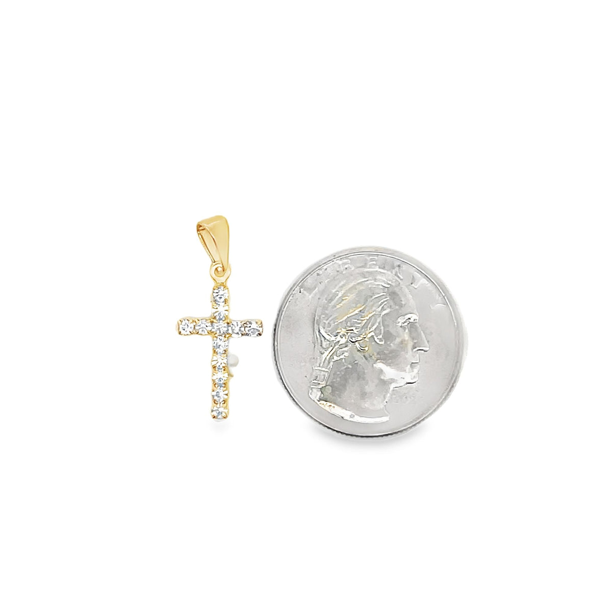 A gold cross pendant encrusted with sparkling diamonds rests next to a quarter coin for size comparison on a white background.