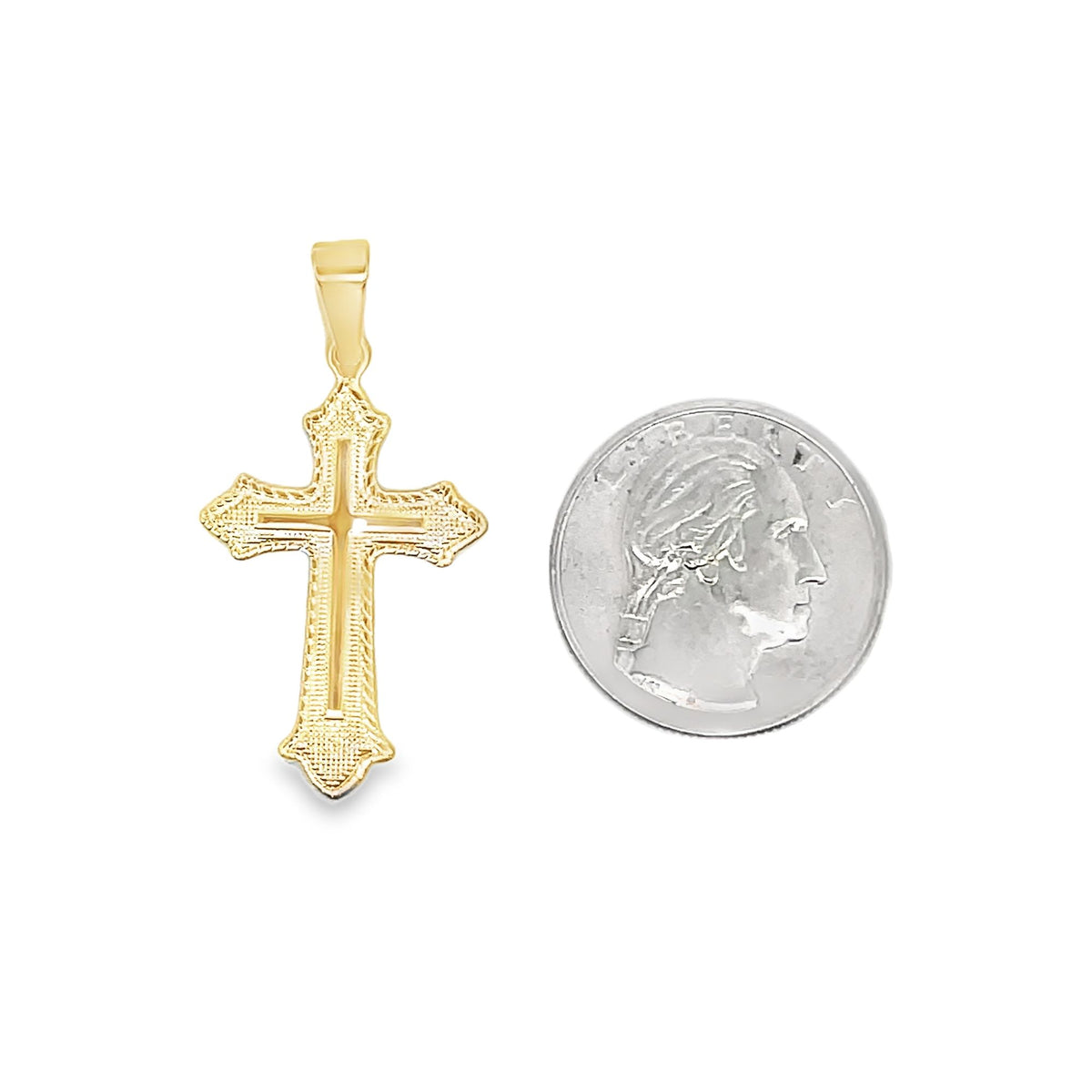 An ornate gold cross pendant rests beside a US quarter for scale.