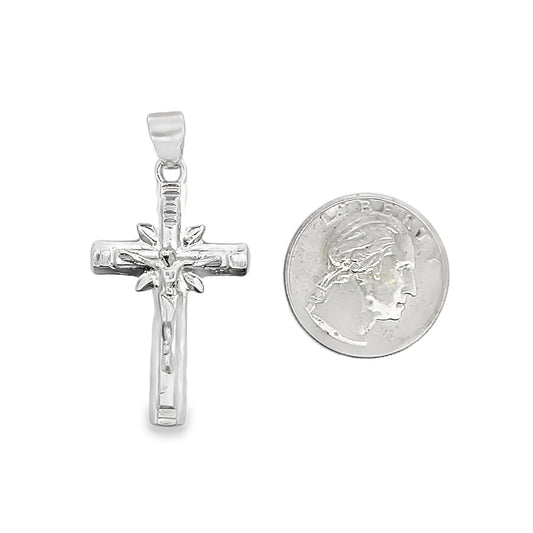 A shiny sterling silver crucifix pendant rests next to a US quarter coin to show its scale.