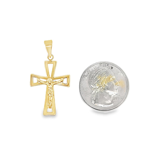 A gold crucifix pendant rests next to a quarter for size comparison on a white background.
