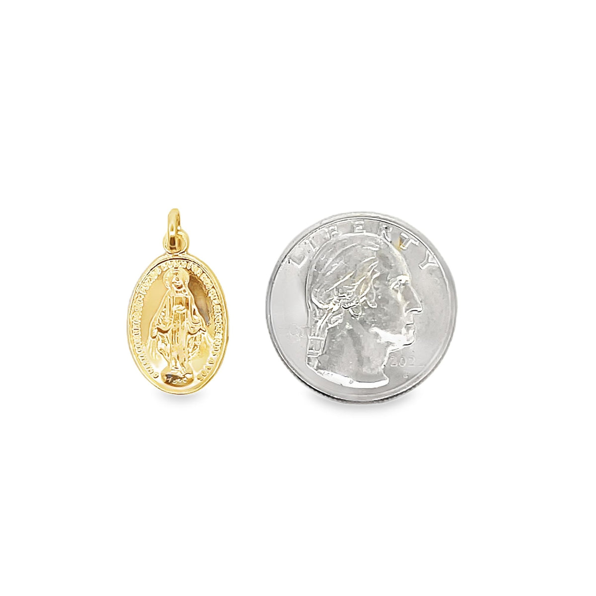 A small gold Miraculous Medal pendant sits next to a US quarter coin to show its size.