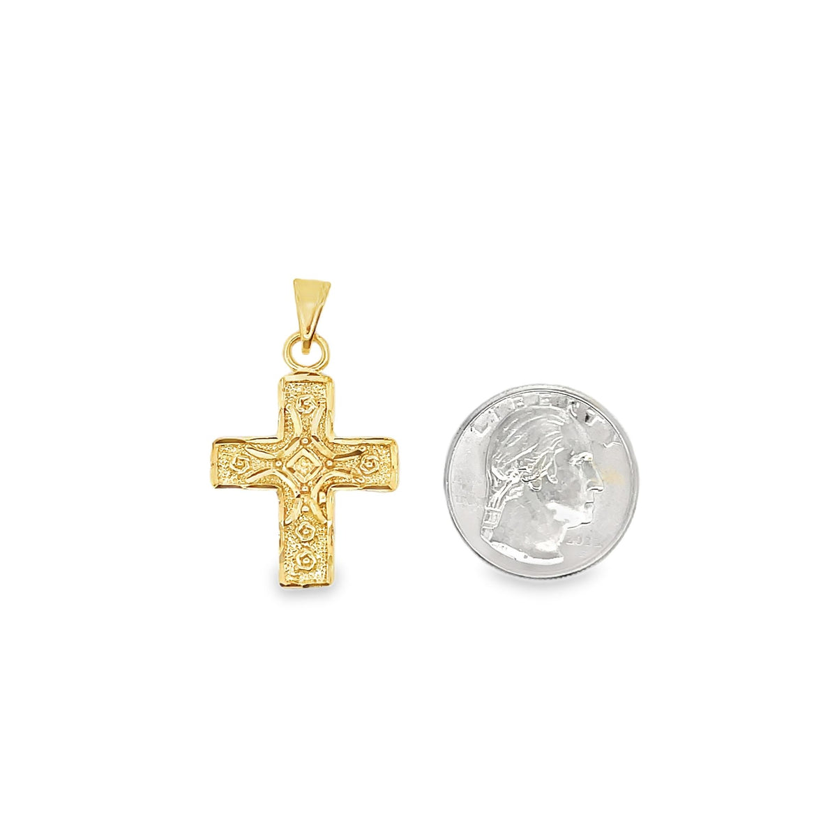 A textured gold cross pendant rests beside a US quarter coin to show its scale.