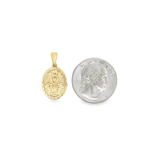 A small gold Miraculous Medal pendant rests beside a US quarter to demonstrate its scale.