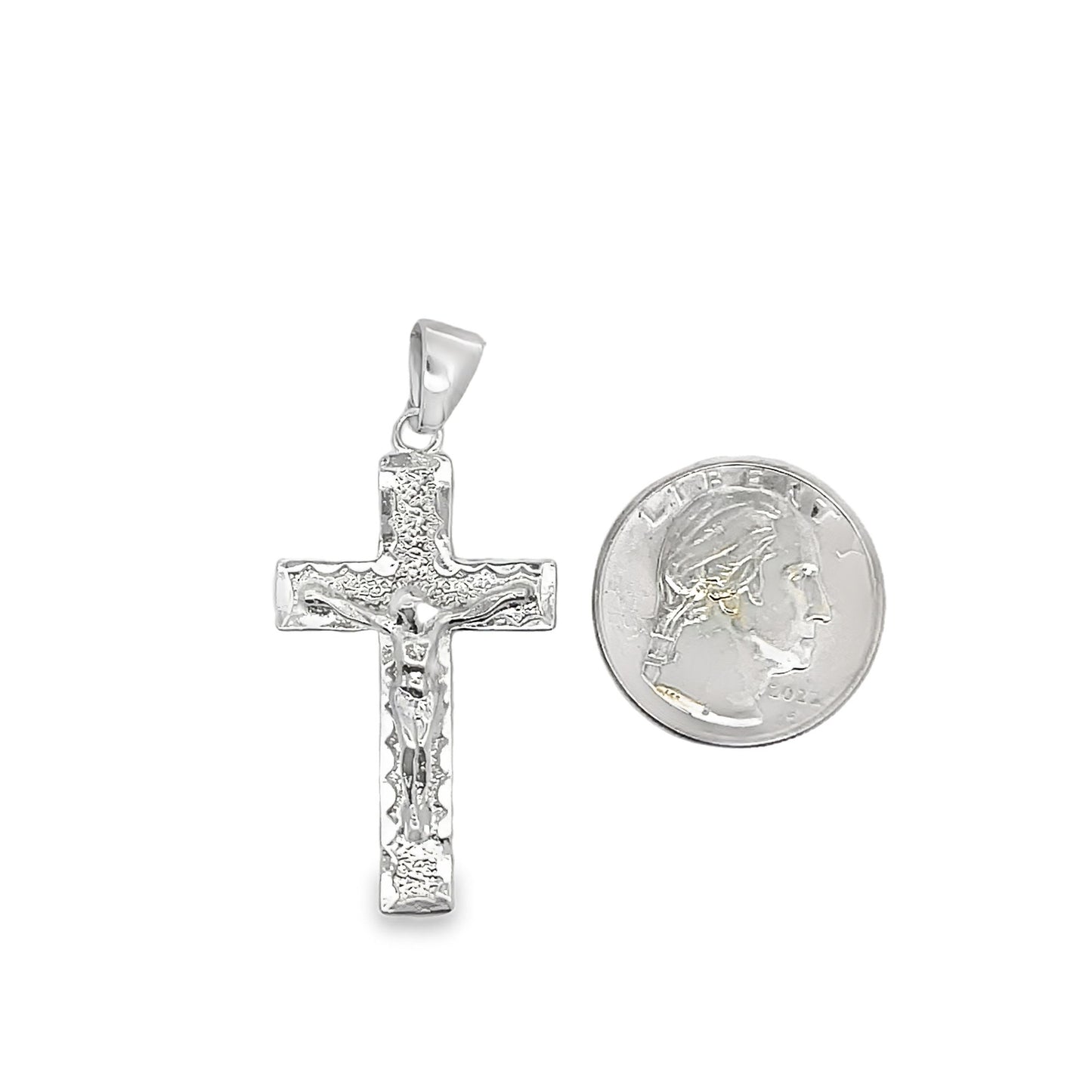 A detailed sterling silver crucifix pendant rests next to a US quarter coin to show its size.