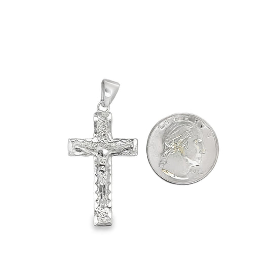 A detailed sterling silver crucifix pendant rests next to a US quarter coin to show its size.