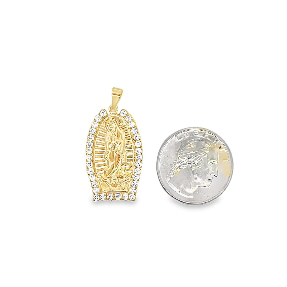 A gold Our Lady of Guadalupe pendant rests next to a US quarter coin to show scale.