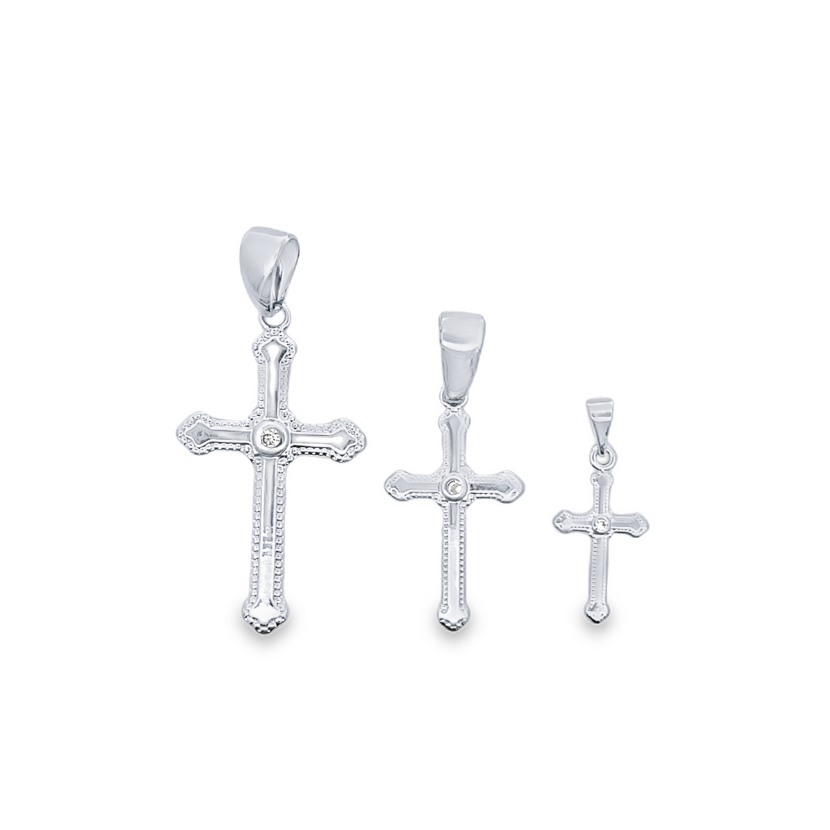 Three polished white gold cross pendants in descending sizes display centered diamond accents against a clean white background.