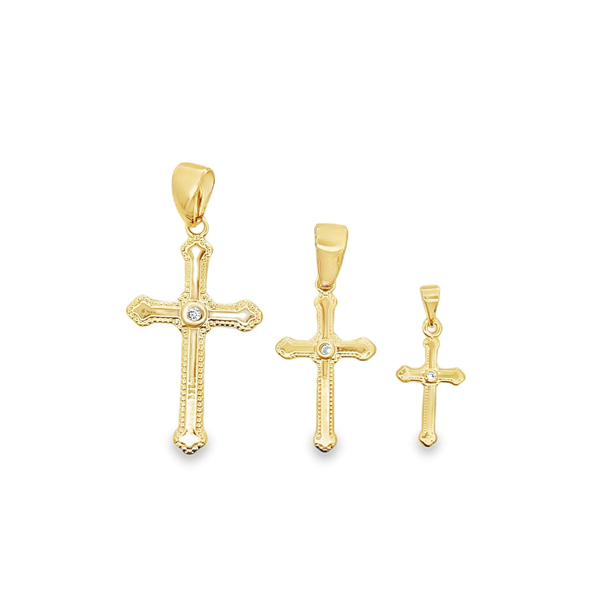 Three graduated gold cross pendants featuring a central diamond accent are displayed in descending size on a plain white background.