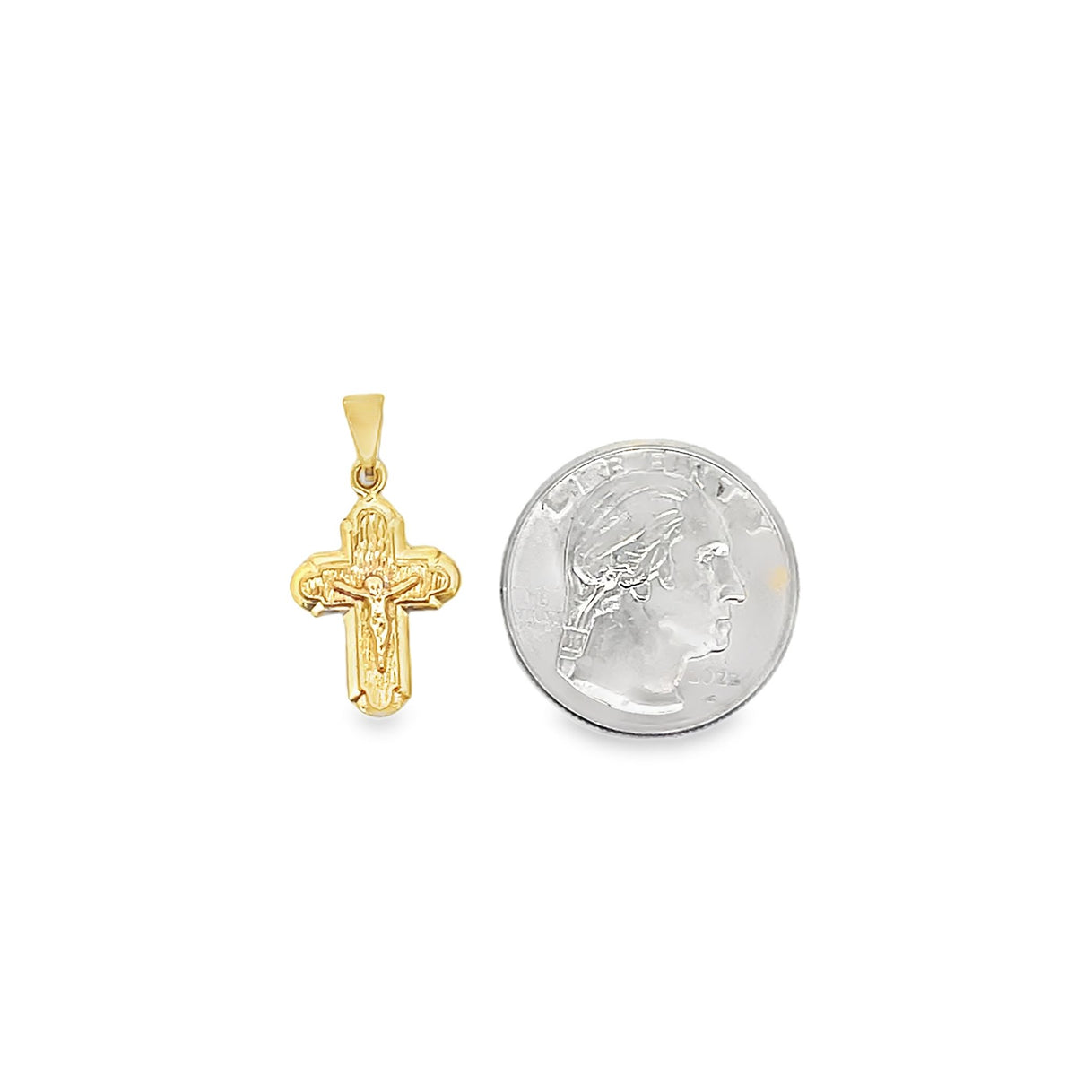 A detailed gold crucifix pendant rests beside a silver US quarter coin for scale.