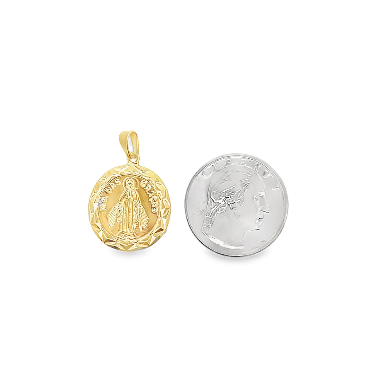 A round gold Our Lady of Grace religious pendant rests beside a US quarter for scale.