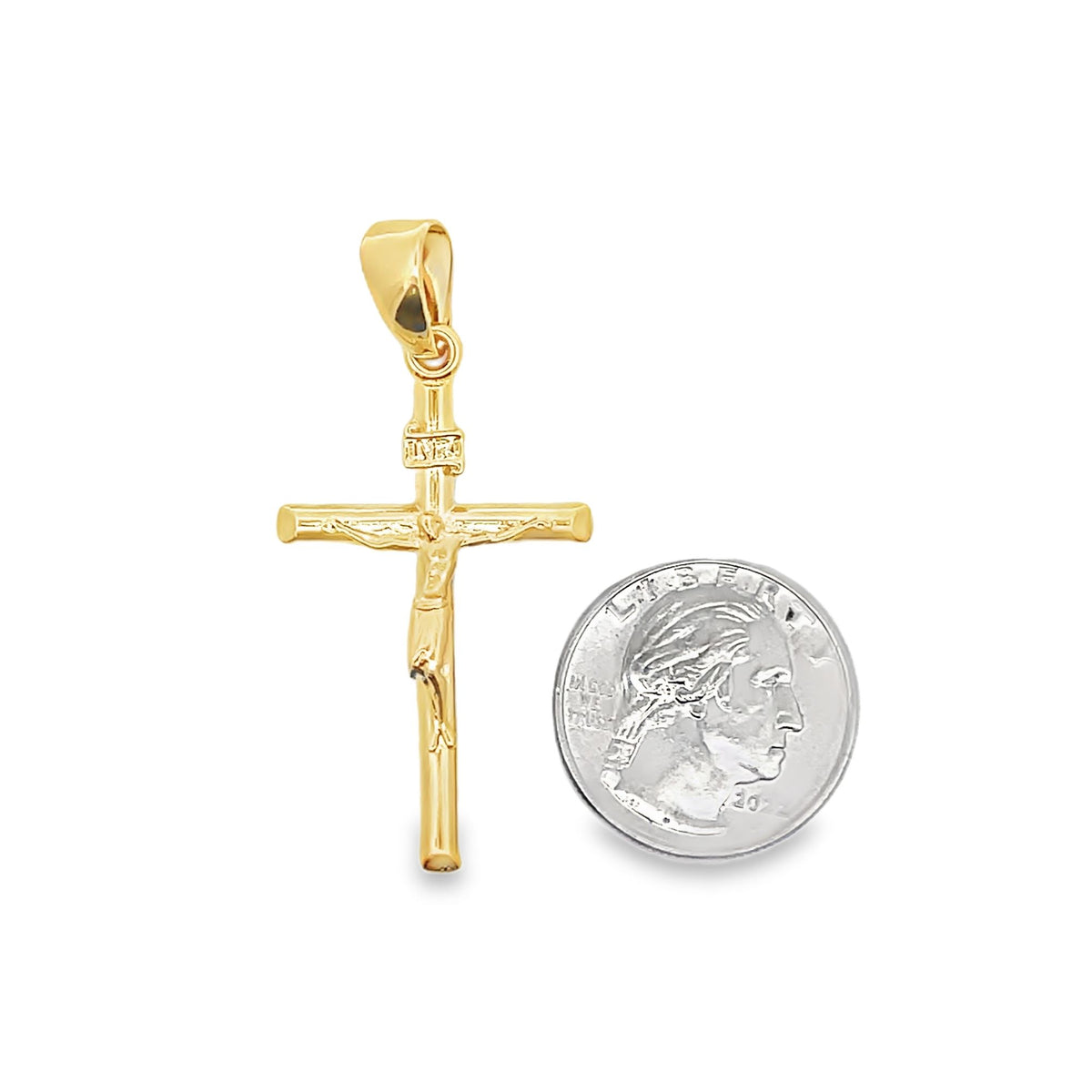 A gold crucifix pendant rests beside a silver US quarter coin to display its size.
