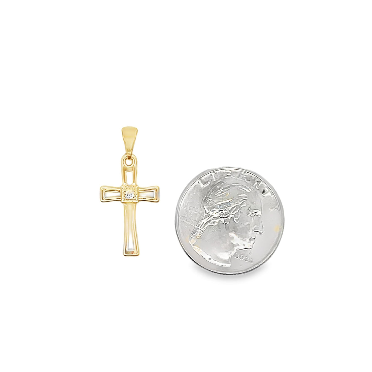 A gold cross pendant featuring a central diamond rests next to a US quarter coin for scale.