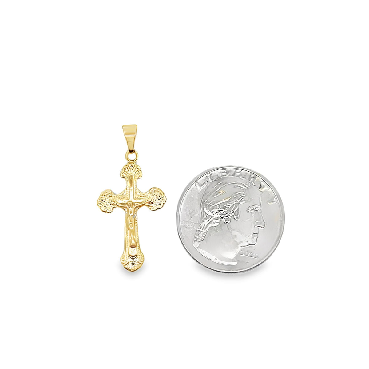 A gold crucifix pendant rests beside a US quarter to display its size.