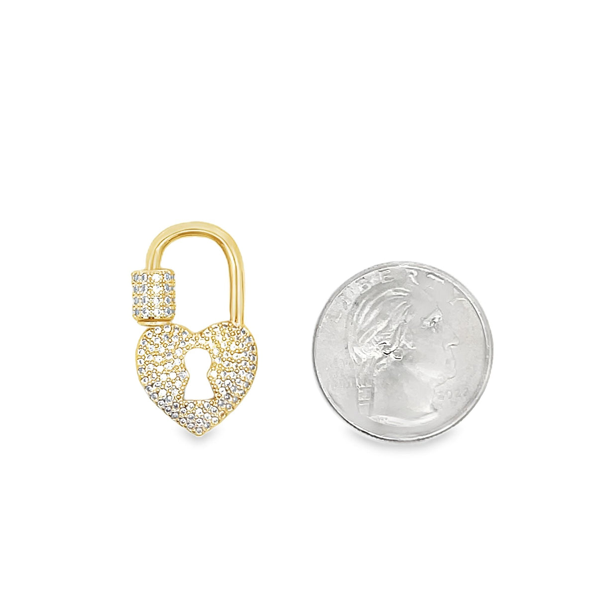 A gold heart-shaped padlock charm encrusted with cubic zirconia stones rests beside a quarter coin to display its actual size.
