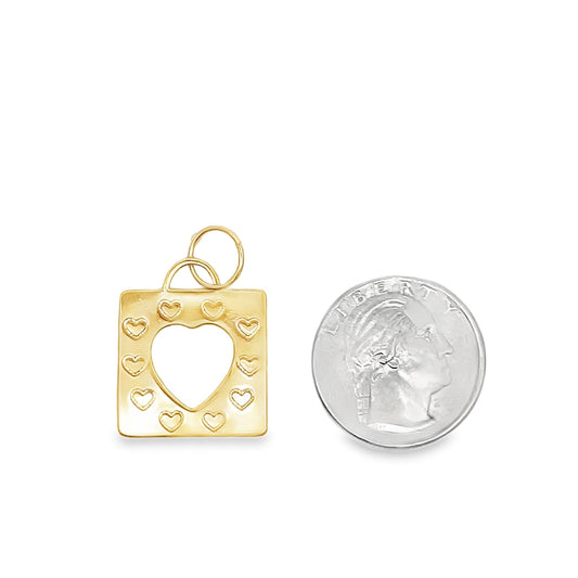 A gold heart charm rests beside a US quarter for scale.