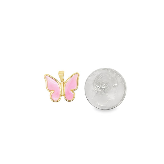 A gold and pink enamel butterfly pendant rests next to a dime for size comparison.