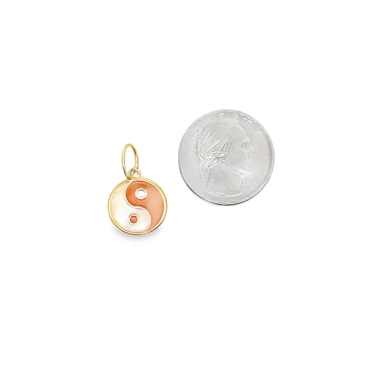 A small gold yin-yang charm with peach and white enamel sits beside a US quarter for scale.