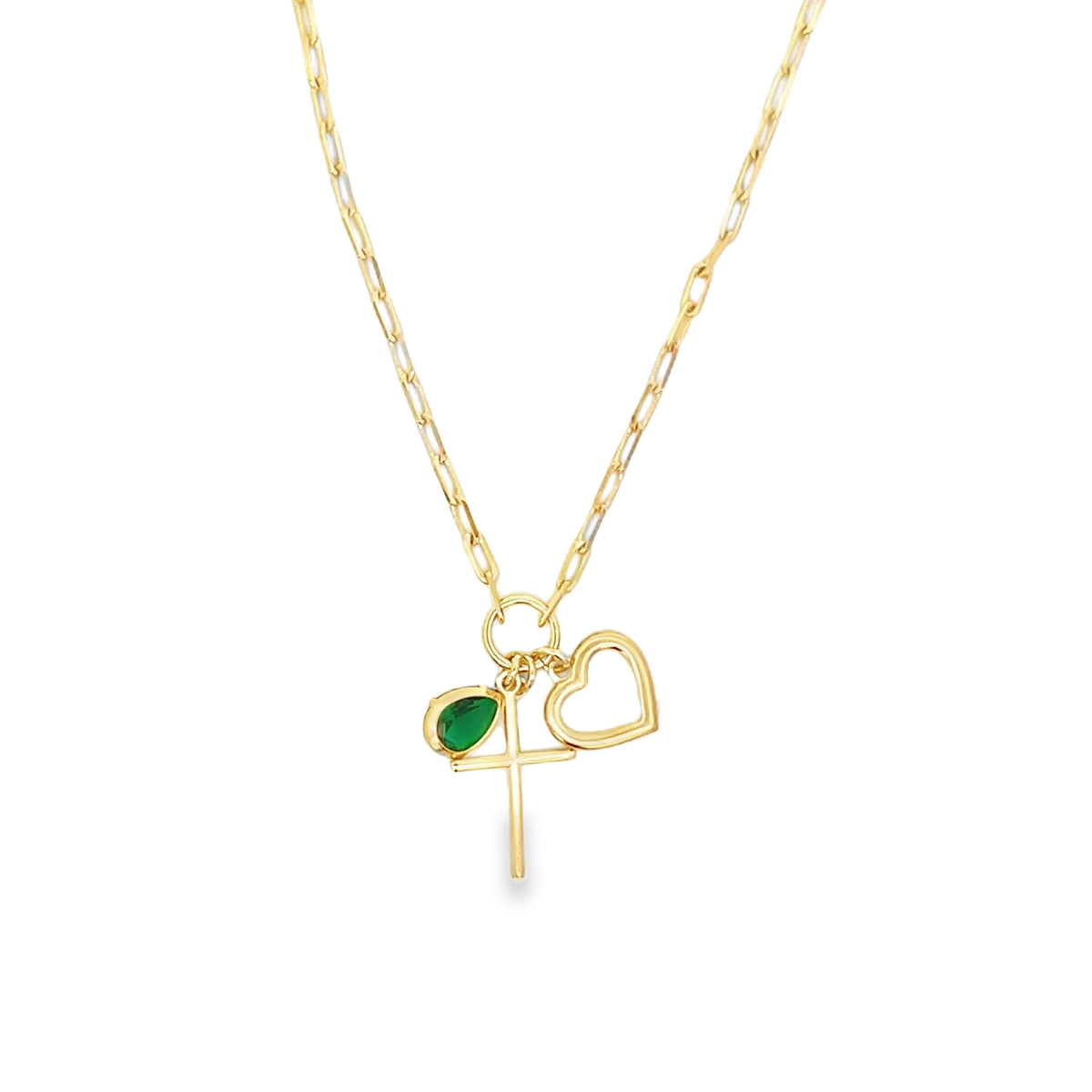 A delicate gold chain necklace features a charm cluster with a cross, an open heart, and a pear-shaped green gemstone.