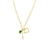 A delicate gold chain necklace features a charm cluster with a cross, an open heart, and a pear-shaped green gemstone.