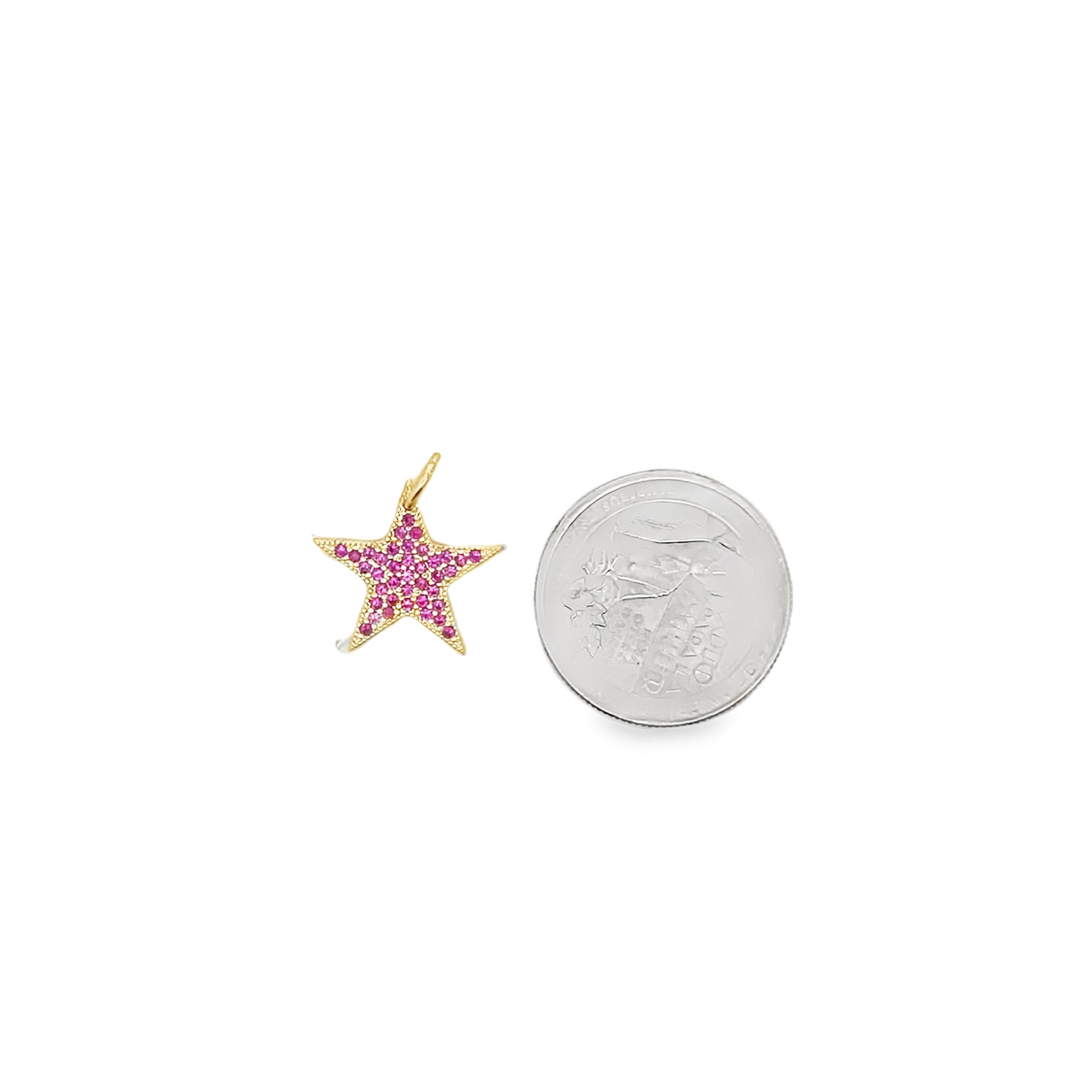A gold star pendant paved with sparkling pink stones rests beside a US quarter for size comparison.