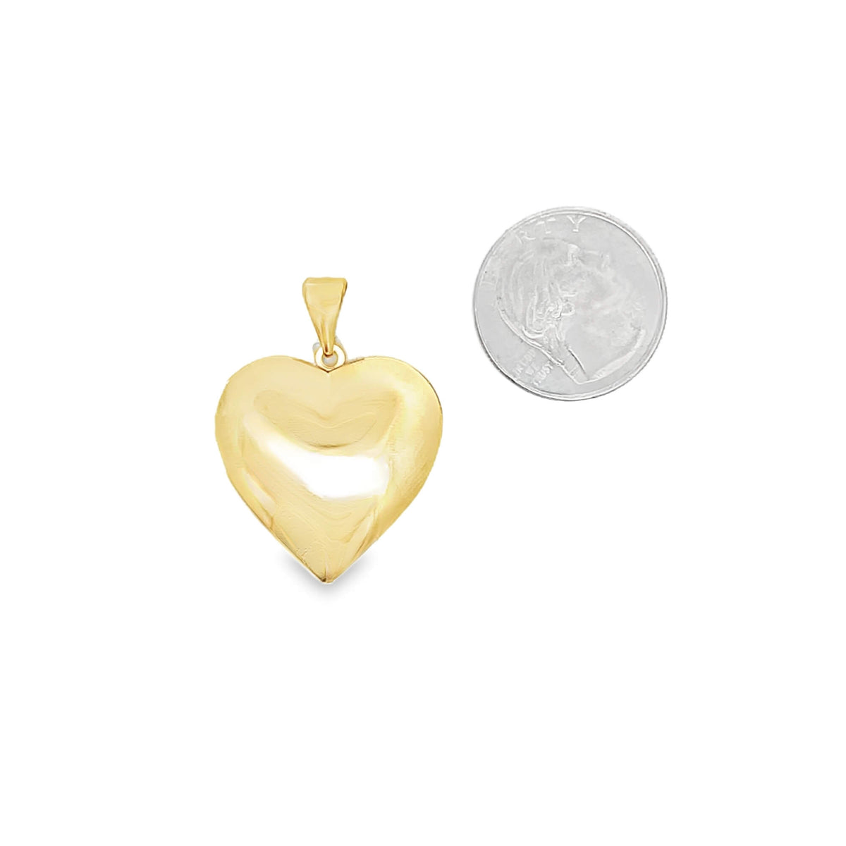 A polished yellow gold puffed heart pendant rests beside a US dime for size comparison.