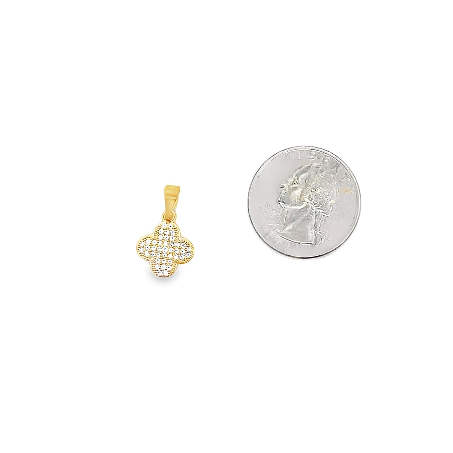 A gold clover pendant encrusted with sparkling cubic zirconia stones rests next to a US quarter coin for scale.