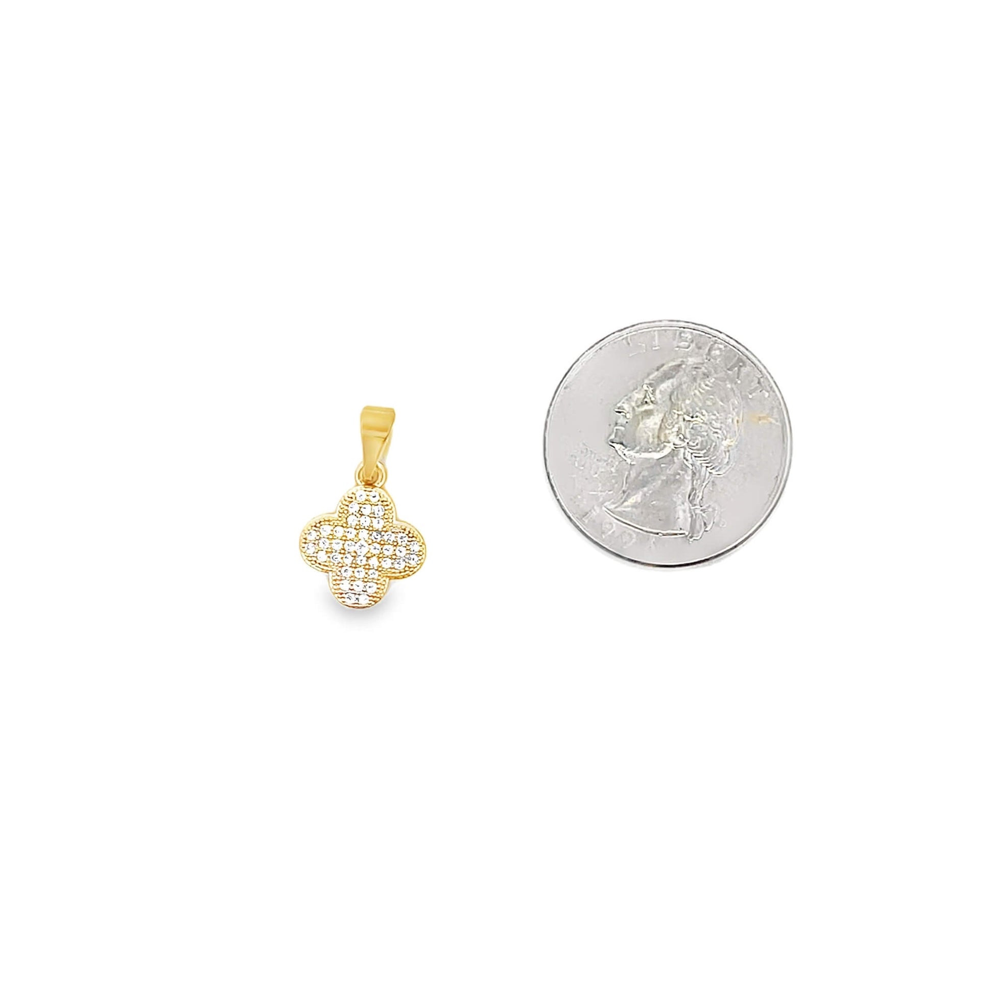 A gold clover pendant encrusted with sparkling cubic zirconia stones rests next to a US quarter coin for scale.