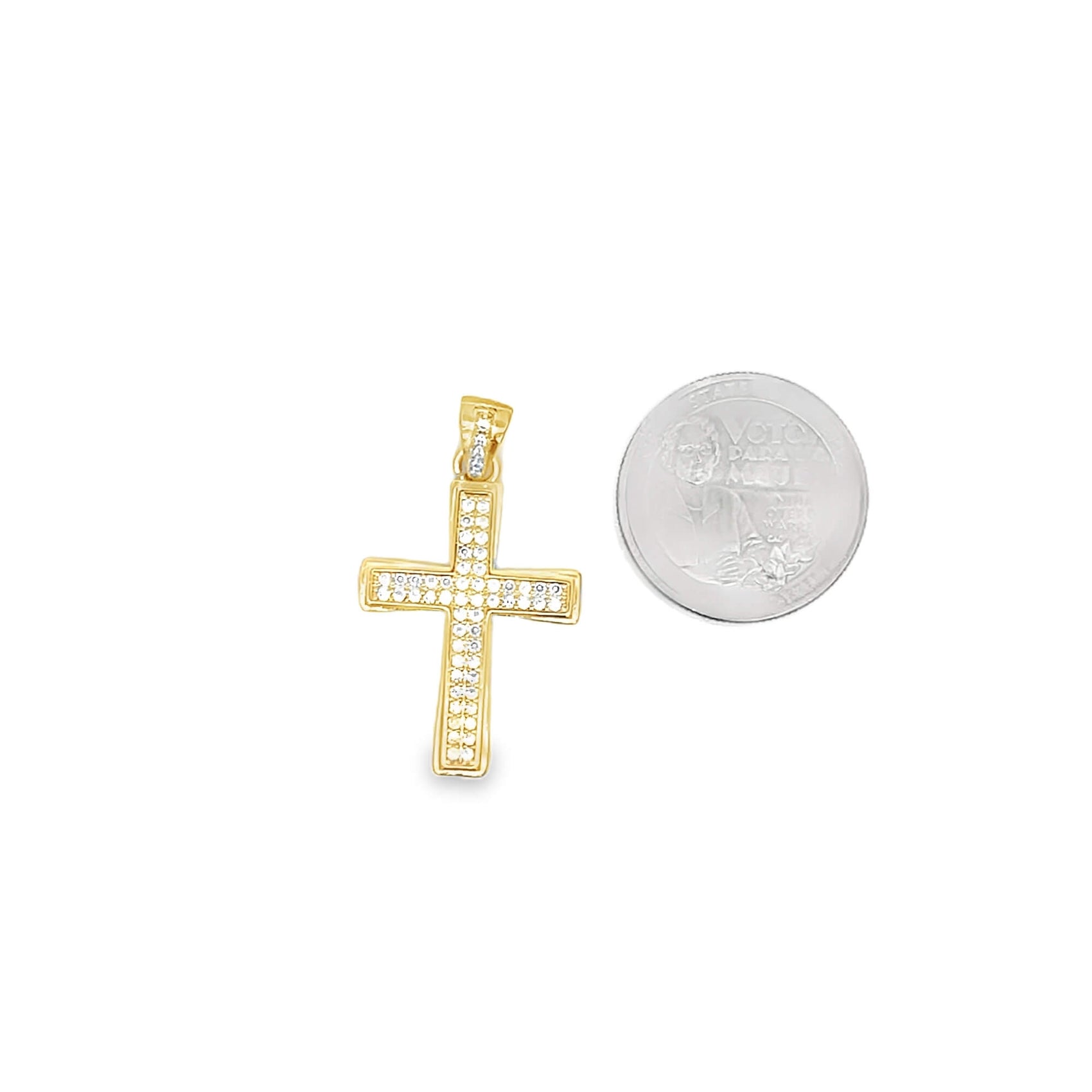 A sparkling diamond cross pendant rests next to a quarter for size comparison.