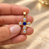 Shop a 18K Gold Filled cross pendant featuring a colorful center stone and sparkling clear CZ accents. Available in multiple stone color options.