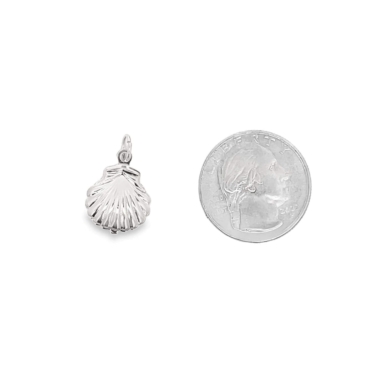 A polished sterling silver seashell charm sits beside a US quarter for size comparison on a white background.