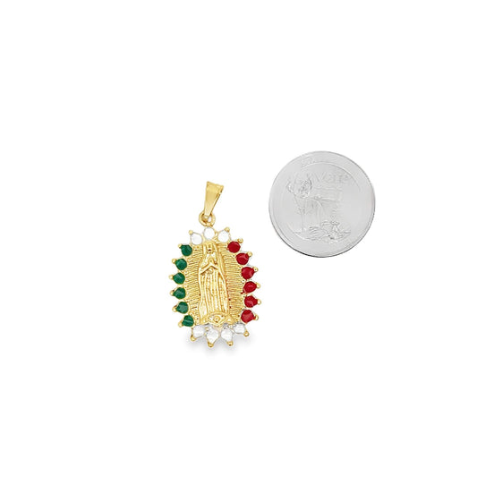 A gold Our Lady of Guadalupe pendant rests next to a coin for scale, showcasing alternating red and green stones framing the central figure.