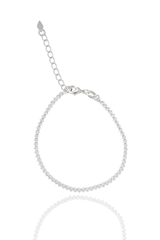 A delicate silver tennis bracelet sparkles against a white background, featuring a lobster clasp and an adjustable chain.