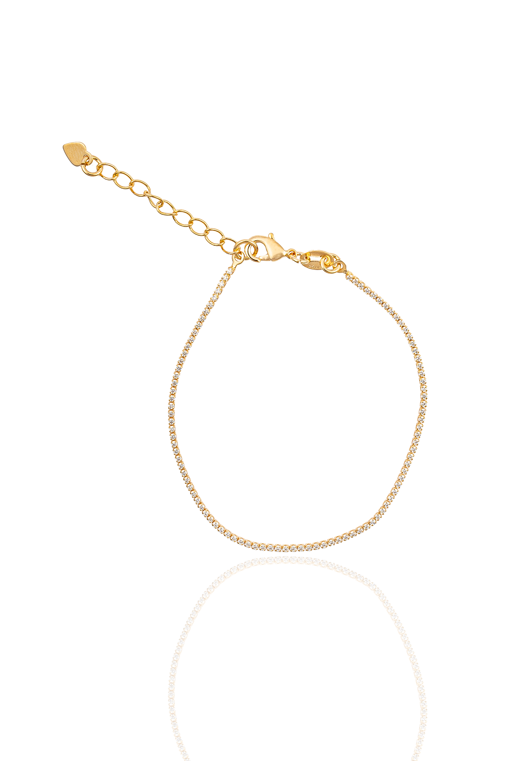 A delicate gold tennis bracelet sparkles against a white background, featuring a lobster clasp and an adjustable chain with a tiny heart charm.