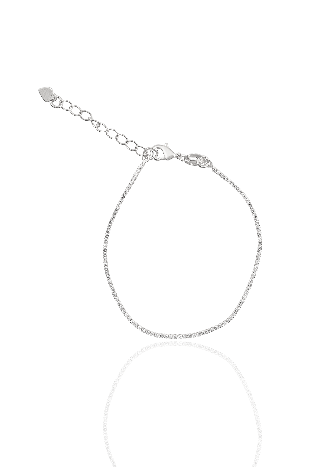 A delicate silver tennis bracelet sparkles against a white background, featuring a lobster clasp and an adjustable chain with a tiny heart charm.