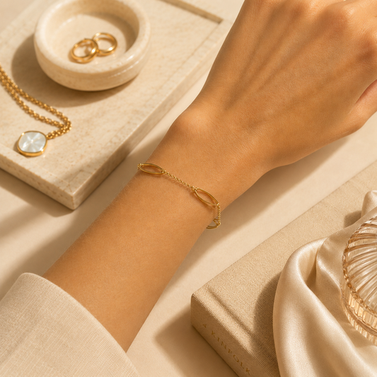 A delicate gold link bracelet adorns the wrist of a woman showcasing minimal jewelry on a neutral aesthetic background.