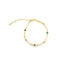 A delicate gold chain bracelet features alternating paperclip links and colorful gemstone bezels against a white background.
