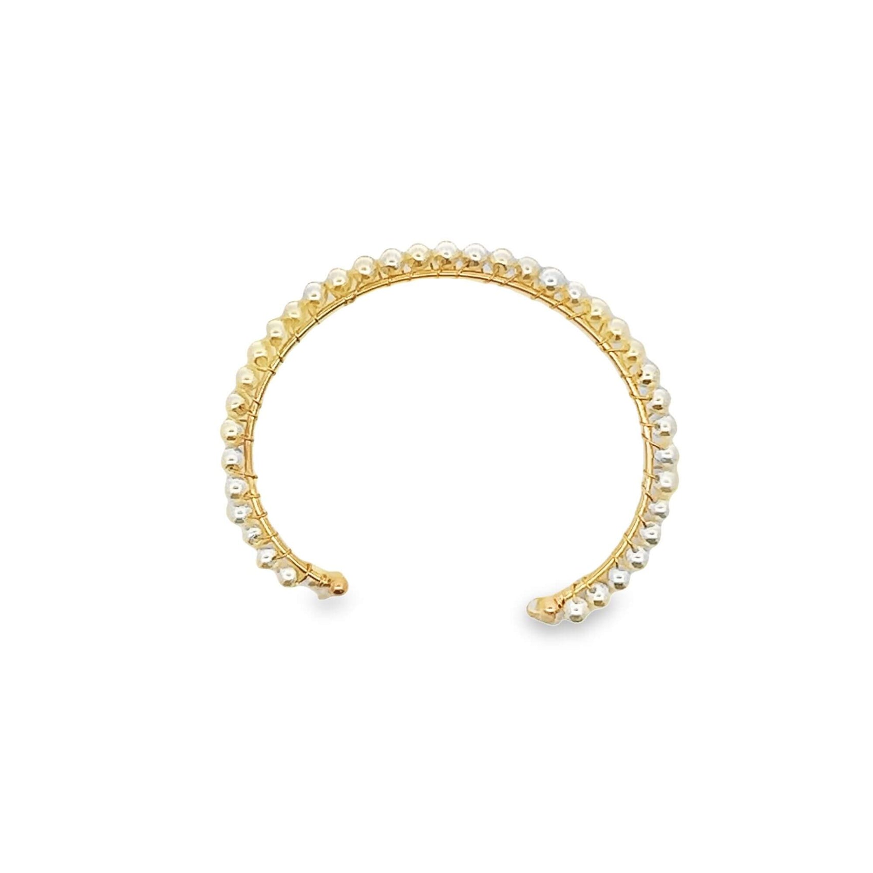 A delicate gold cuff bracelet features an open-circle design lined with tiny white pearls.