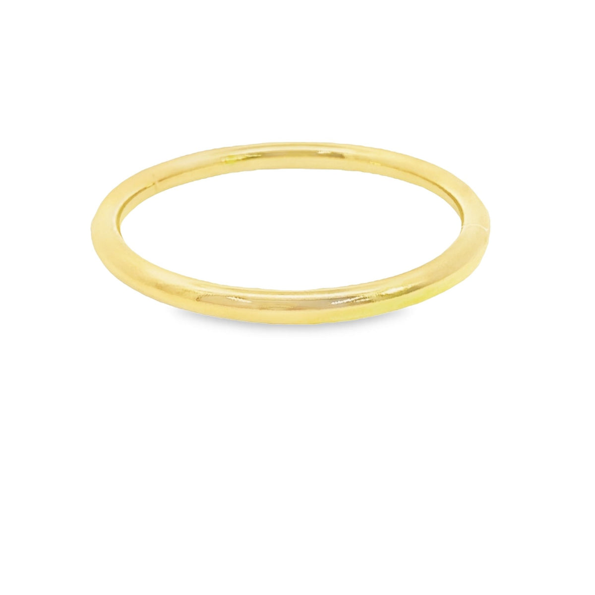 A smooth, polished yellow gold band rests on a clean white surface.