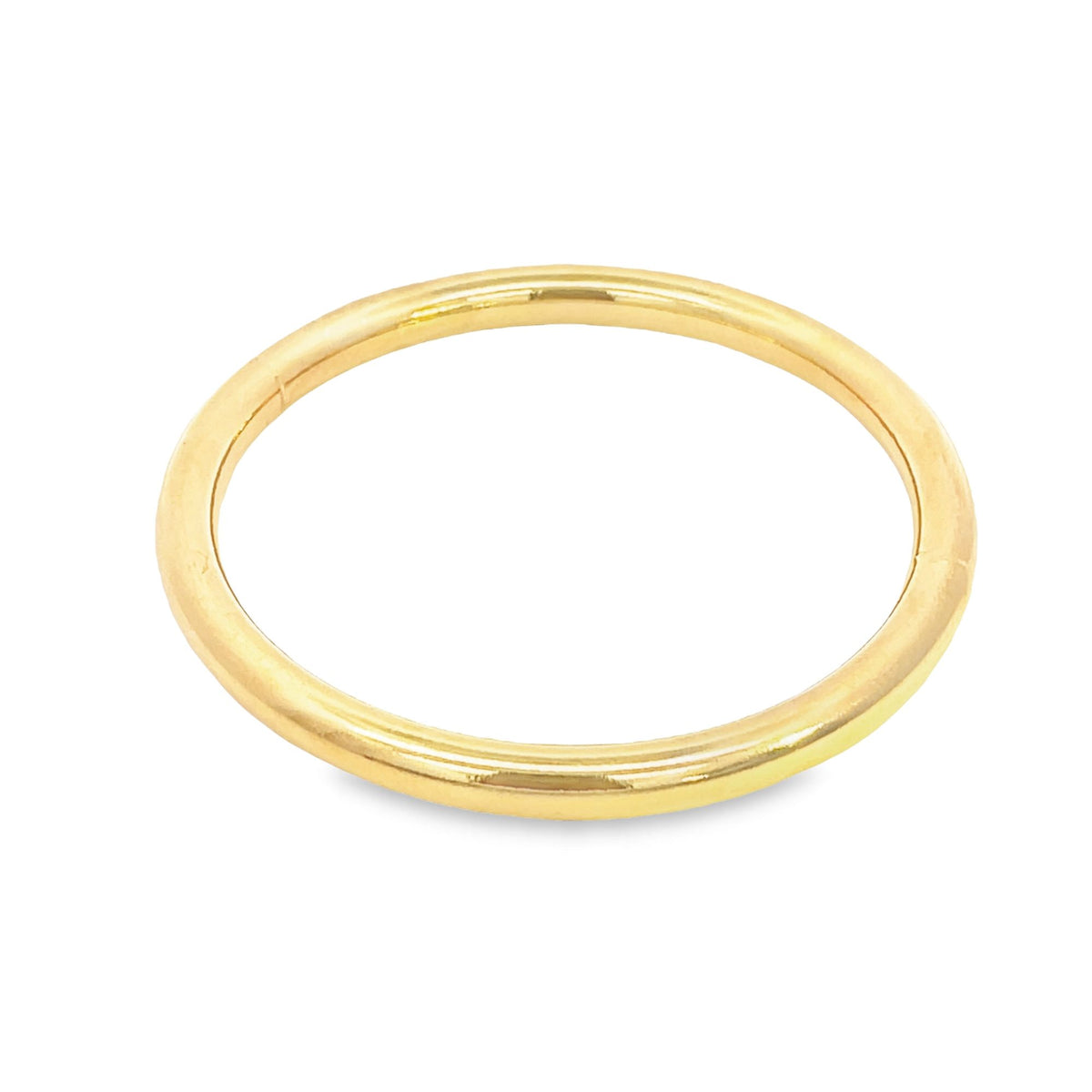 A simple polished yellow gold band ring rests on a clean white background.