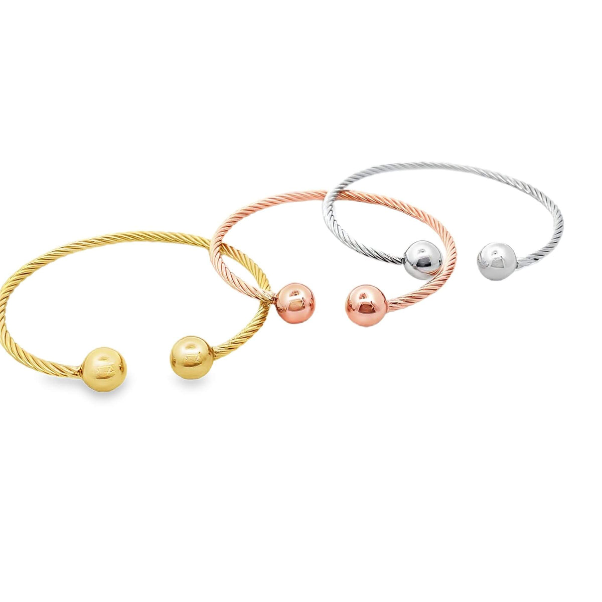 Three twisted cable-wire cuff bracelets in yellow gold, rose gold, and sterling silver feature polished ball ends against a clean white background.