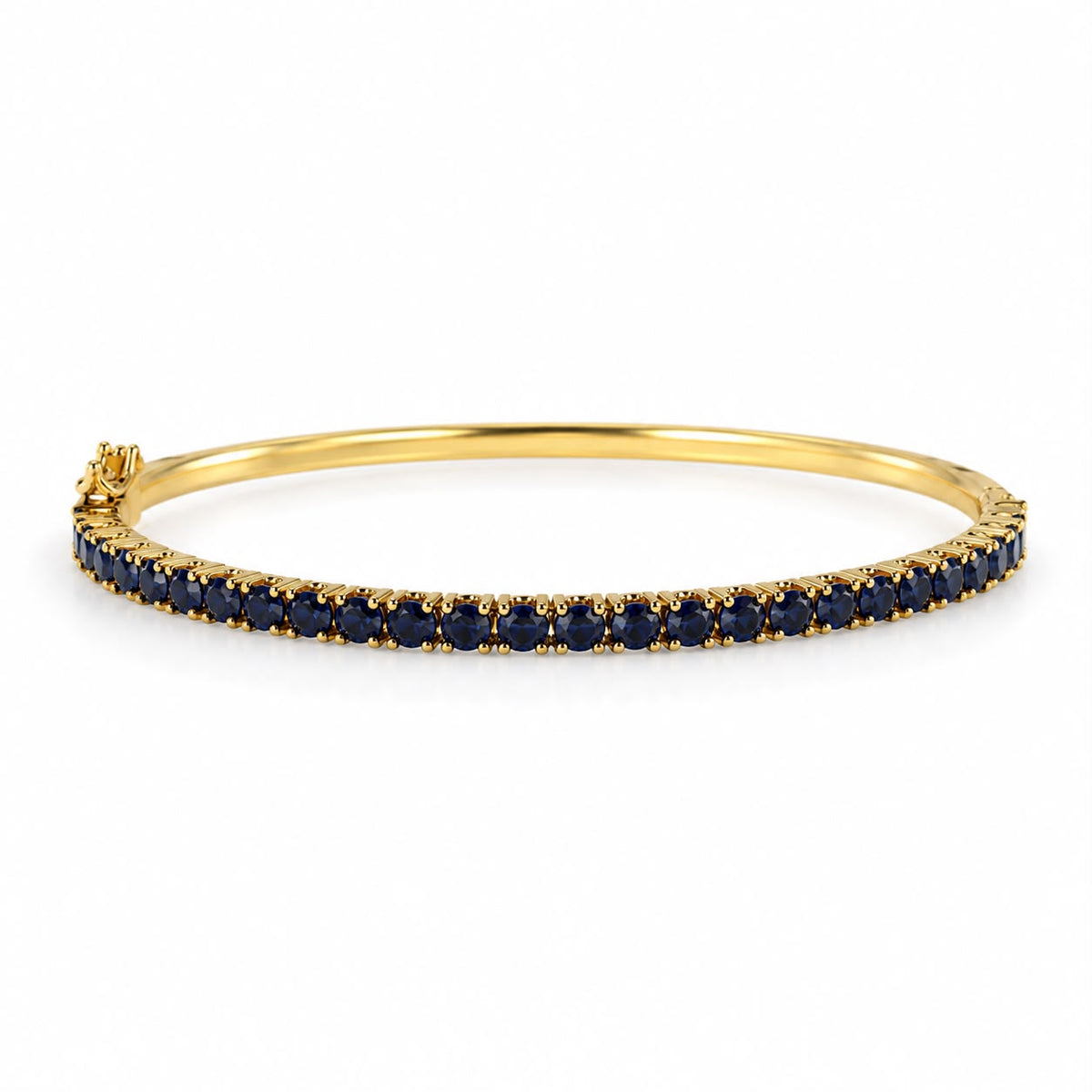 A yellow gold bangle bracelet features a continuous row of round dark blue sapphires set against a clean white background.