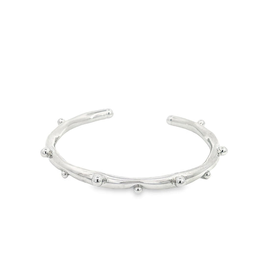 A sleek silver cuff bracelet features delicate, evenly spaced metal beads along its textured band.