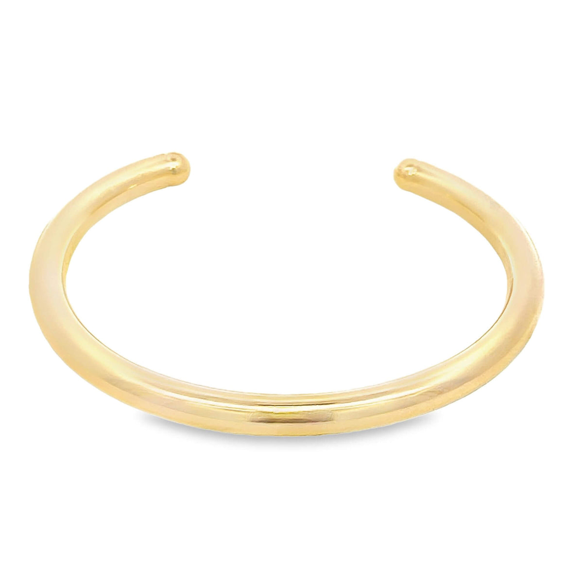 A minimalist polished gold cuff bracelet rests against a clean white background.